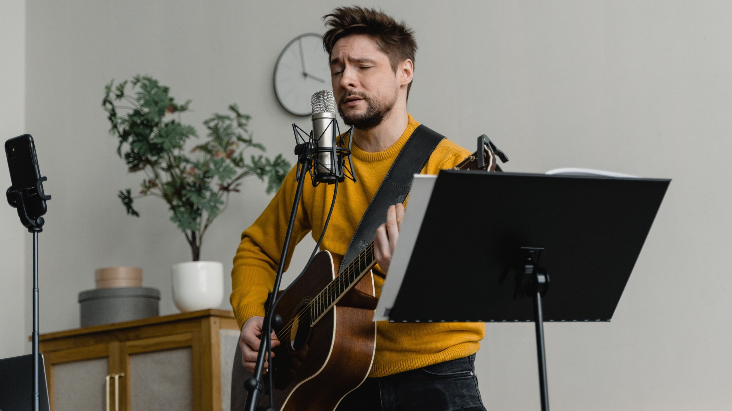 Praktyczny prezent dla muzyka - gitarzysta nagrywający piosenkę w salonie